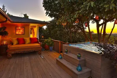 a patio with a hot tub and a couch on a deck at Bella Vista by Paradise Retreats in Carpinteria