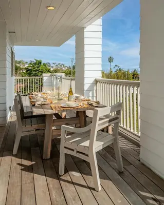 a wooden table and chairs on a porch with a table and chairs at Ocean Breeze Abode and Bungalow by Paradise Retreats in Summerland