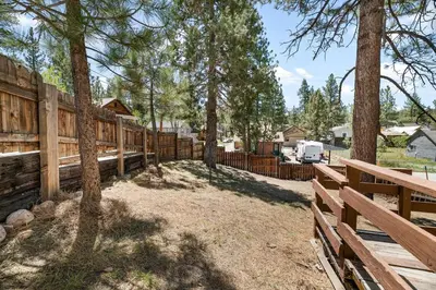 a wooden fence in a yard with trees at Modern Lake Cabin for Family, Friends and Pets! in Big Bear Lake