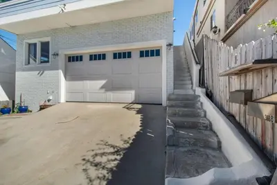 a garage with a white garage door and a fence at Luxury Ocean View Condo Steps To The Sand VIEWS in Manhattan Beach