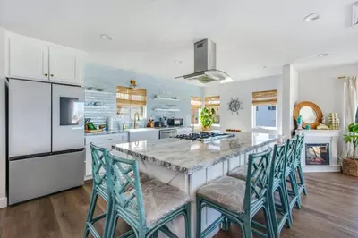 a kitchen with a large kitchen island with blue chairs at Luxury Ocean View Condo Steps To The Sand VIEWS in Manhattan Beach
