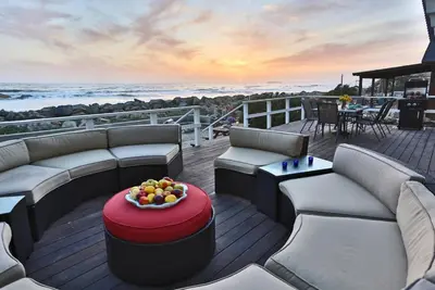 a deck with couches and a bowl of fruit on a table at Seacliff Beach House by Paradise Retreats in Ventura