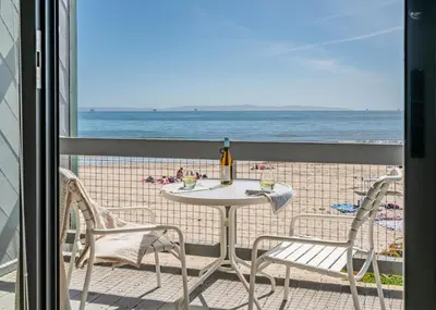 a table and chairs on a balcony with the beach at Seahorse Cottage by Paradise Retreats in Carpinteria