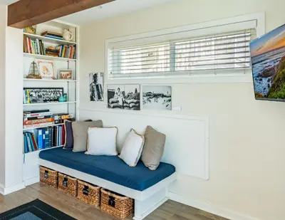 a bench in a room with a window and bookshelves at Seahorse Cottage by Paradise Retreats in Carpinteria