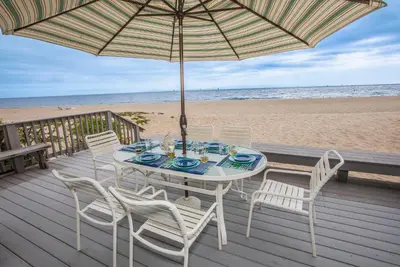a table with chairs and an umbrella on the beach at Seahorse Retreat by Paradise Retreats in Carpinteria