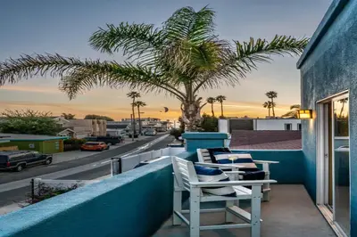 a couple of chairs sitting on a balcony with a palm tree at Summer Sunset by Paradise Retreats in Ventura
