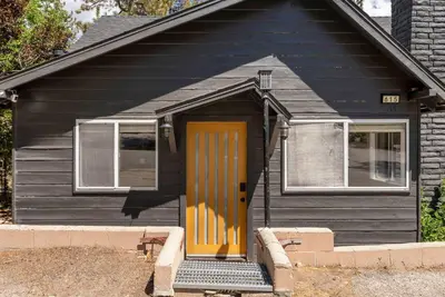 a black house with a yellow door and windows at Newly Renovated Villa 6 Beds Fenced-in Backyard in Big Bear Lake