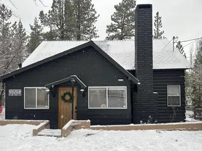 a black house with a door in the snow at Newly Renovated Villa 6 Beds Fenced-in Backyard in Big Bear Lake