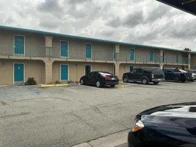 a large building with cars parked in a parking lot at Crzy 8 Motel in Orange