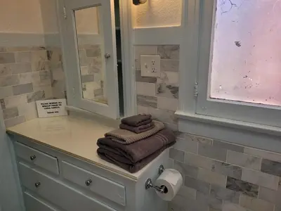 a bathroom with towels on a counter and a mirror at Beautiful Bungalow Five in Hollywood! in Los Angeles