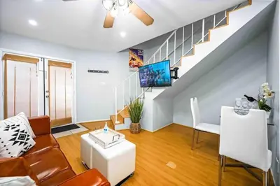 a living room with a couch and a tv and stairs at Elegant Beachside 2 Bed 2 Bath in Long Beach