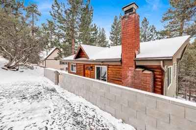 a log cabin in the snow with a brick chimney at Suenos Azules #2517 in Fawnskin