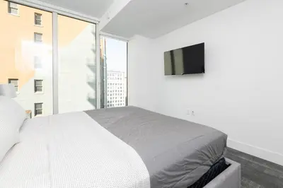 a white bedroom with a bed and a large window at Stylish 3BR High-Rise with Pool, Hot Tub & Rooftop Views in Los Angeles