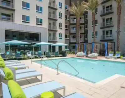 a large swimming pool with chairs and a building at Cozy 2 Bedroom Apartment Near Disneyland and Anaheim Convention Center in Orange