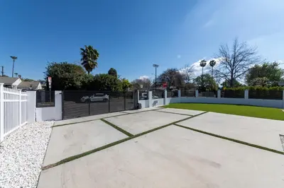 a driveway with a white fence and a yard at Gated Private Home next to Universal Studios in Van Nuys County Court Heliport