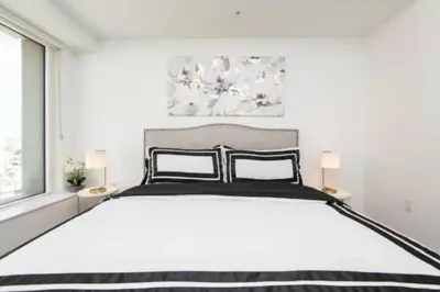a white bedroom with a large bed with two lamps at Snazzy 3 Bedroom High Rise with Pool, Hot Tub and Rooftop Deck in Los Angeles
