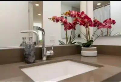 a bathroom with a sink with flowers and a mirror at Beautiful 3 Bedroom High Rise with Pool, Hot Tub and Rooftop Views in Los Angeles