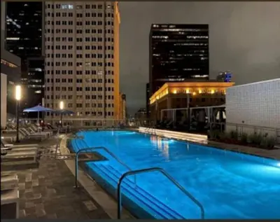 a large swimming pool in a city at night at Beautiful 3 Bedroom High Rise with Pool, Hot Tub and Rooftop Views in Los Angeles