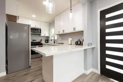 a kitchen with white cabinets and a stainless steel refrigerator at Spacious 3 Bedroom 2 Bathroom Apartment with Free Onsite Parking in Los Angeles