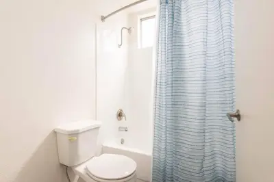 a bathroom with a toilet and a blue shower curtain at Snazzy 2 Bedroom Pad with Rooftop Pool and Hollywood Sign View in Los Angeles