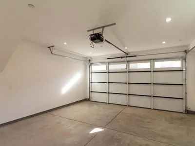 an empty garage with white garage doors and a spotlight at Modern Luxe Retreat 3-Bedroom #3 in Los Angeles