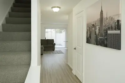 a living room with stairs and a chair and a painting at Spacious 2BR Townhouse - 3 Queens - Sleeps 8 in Redondo Beach