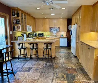a large kitchen with wooden cabinets and bar stools at Cheerful Single Story 3-bedroom home w pool table in Santa Clarita