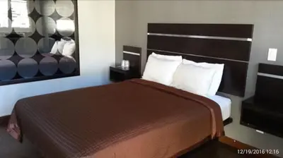 a bedroom with a large bed with a large headboard at El Grande Motel in South Gate