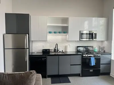 a kitchen with white cabinets and a stainless steel refrigerator at The NoHo Artist Nook in Burbank