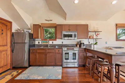 a kitchen with wooden cabinets and stainless steel appliances at Blue Ocean View Retreat - Minutes to Beach in Summerland