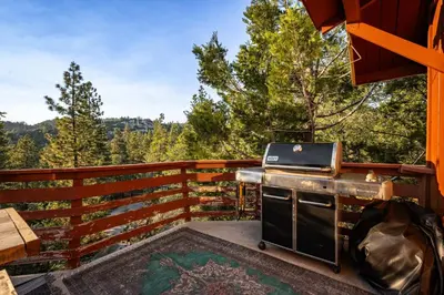 a grill on a deck with a view of the mountains at Perch - Peaceful ECO Cedar Hot Tub AC EV Mountain Views in Running Springs