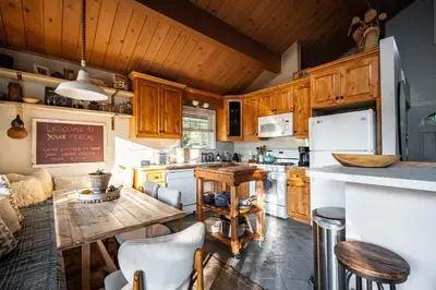 a kitchen with wooden cabinets and a wooden table at Perch - Peaceful ECO Cedar Hot Tub AC EV Mountain Views in Running Springs