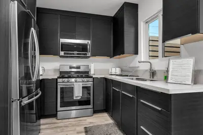 a kitchen with black cabinets and stainless steel appliances at Claudia's Guest House in Los Angeles