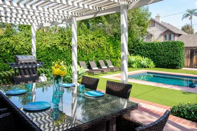 a dining table under a white pergola next to a pool at F-39 Helena in Anaheim