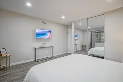 a white bedroom with a bed and a tv at F-65 Adventure House in Anaheim