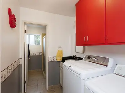 a laundry room with a washing machine and red cabinets at F-21 Castle House 1 in Anaheim