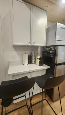 a kitchen with white cabinets and a black refrigerator at Tiny House Living with In Unit Laundry Steps from Kaiser in Litton Industries Heliport