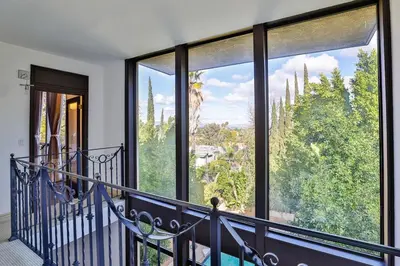 a balcony with large windows with a view of trees at 6BR-Music Studio-Pool-Spa & Games in Sherman Oaks