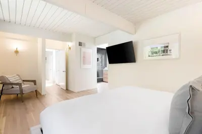 a white bedroom with a bed and a chair at Malibu Reserve by Stay Awhile Villas in Malibu