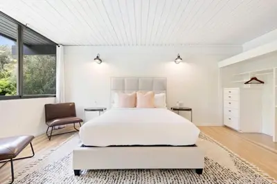 a white bedroom with a bed and a chair at Malibu Reserve by Stay Awhile Villas in Malibu