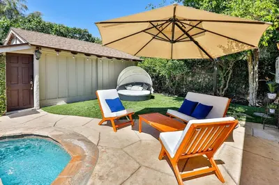 a patio with two chairs and an umbrella next to a pool at City Paradise Saltwater Pool-Spa and Ping-Pong in Los Angeles