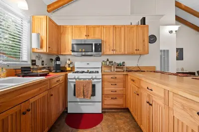 a kitchen with wooden cabinets and a white stove top oven at Bluebird Cabin, Indoor Fireplace, Next to Lake! in Green Valley Lake