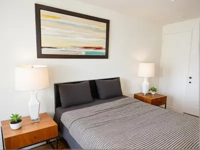 a bedroom with a bed and two lamps and a painting at Boutique KTown Stays With Breathtaking Rooftop Views in Los Angeles