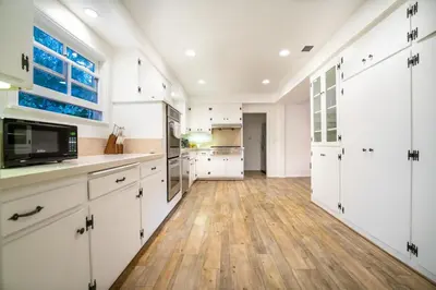 a kitchen with white cabinets and a wooden floor at Pool & Spa Ping-Pong Mini-Golf & 5BR in Sherman Oaks