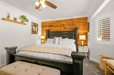 a bedroom with a bed with a wooden wall at Hummingbird Corner Pet Friendly Great Location Jacuzzi in Big Bear Lake