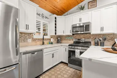 a kitchen with white cabinets and a stainless steel refrigerator at Hummingbird Corner Pet Friendly Great Location Jacuzzi in Big Bear Lake