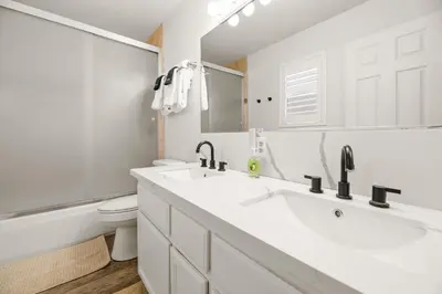 a white bathroom with two sinks and a toilet at Hummingbird Corner Pet Friendly Great Location Jacuzzi in Big Bear Lake