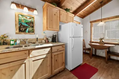 a kitchen with wooden cabinets and a white refrigerator at Comstock Cabin by Rather Be Properties in Big Bear Lake