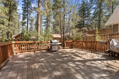 a wooden deck with a grill and trees at Comstock Cabin by Rather Be Properties in Big Bear Lake