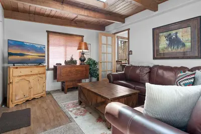 a living room with a leather couch and a table at Comstock Cabin by Rather Be Properties in Big Bear Lake